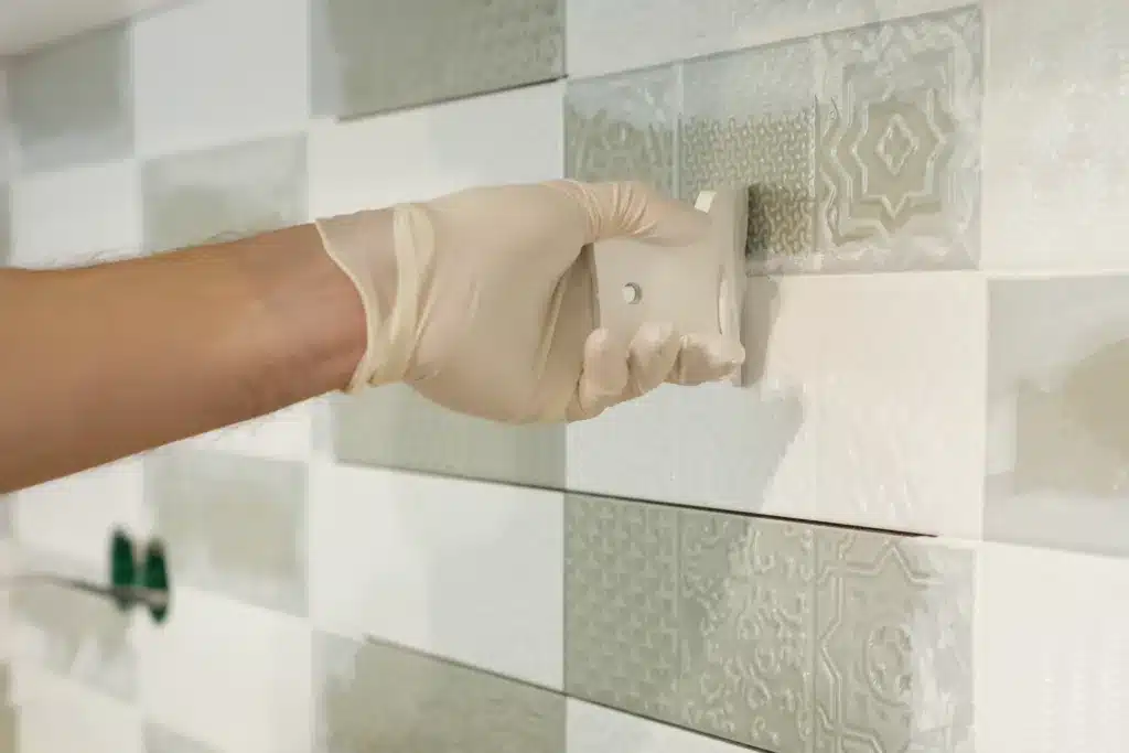 Closeup of tiler hand rubbing tile, Installing and grouting decorative finishes in environments with an high aesthetic value. Two-component, decorative, acid resistant epoxy grout. epoxy on tile